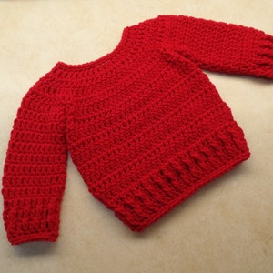 May include: A red crocheted sweater with long sleeves.