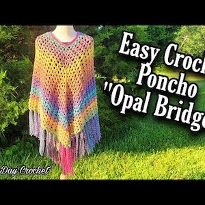 May include: A multi-coloured crochet poncho in shades of yellow, orange, pink, blue, and purple. The poncho has a fringed hem and is displayed on a mannequin. The text "Easy Crochet Poncho 'Opal Bridge'" is visible.