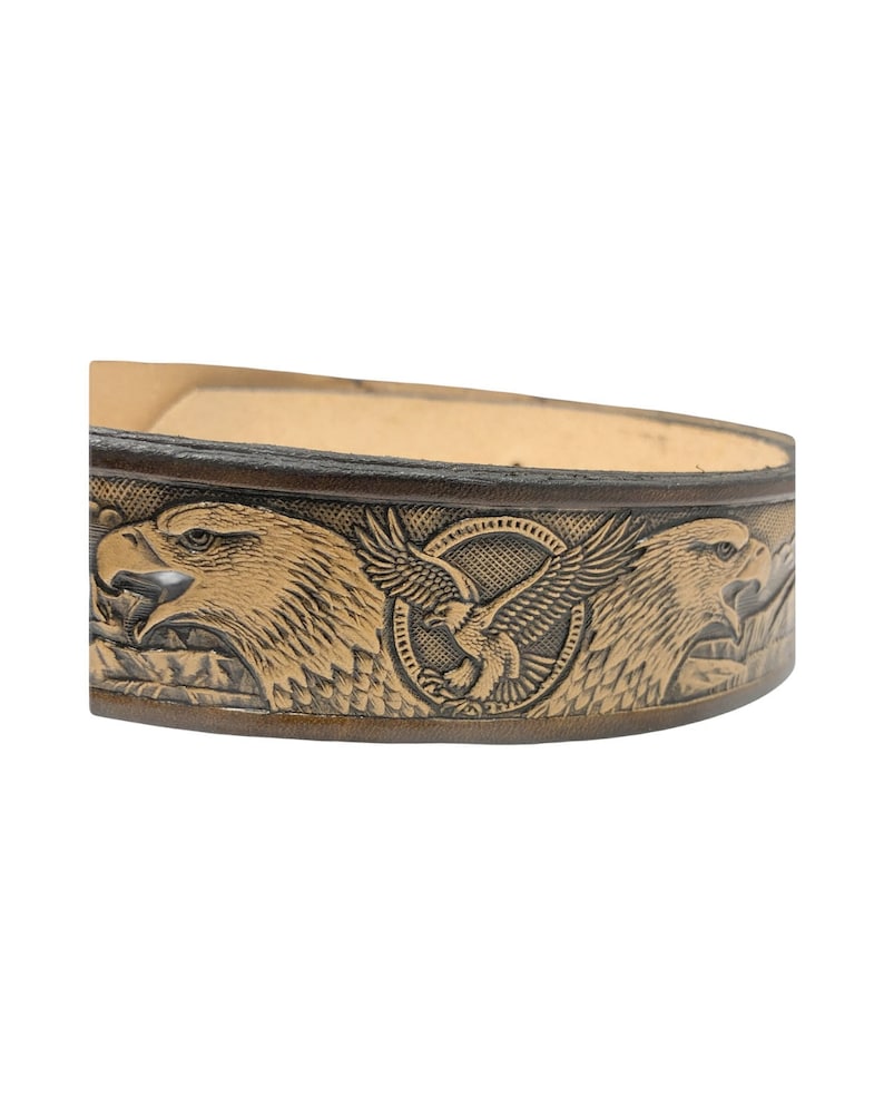 Peut inclure: Une ceinture en cuir marron avec un motif en relief de deux aigles aux ailes d&eacute;ploy&eacute;es. Les aigles sont dans un cercle avec un plus petit aigle au centre.
