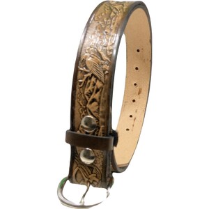 Peut inclure: Une ceinture en cuir marron avec un motif en relief d'oiseaux et de montagnes. La ceinture a une boucle argent&eacute;e et mesure 2,5 cm de large.