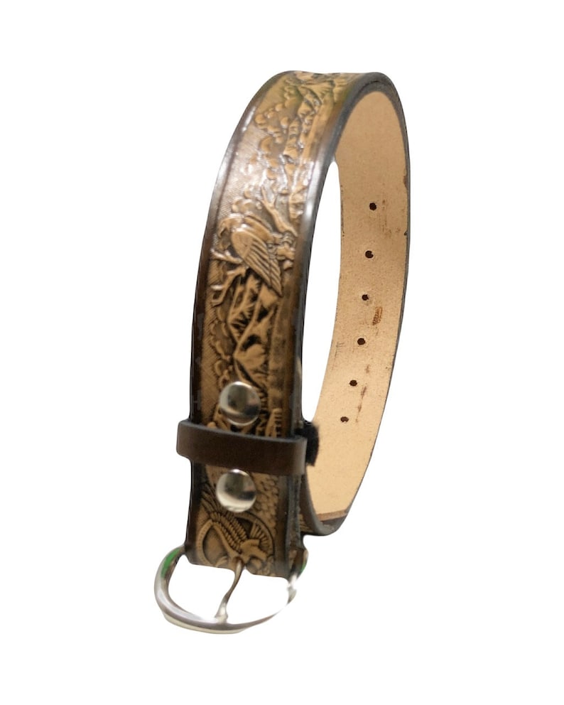 Peut inclure: Une ceinture en cuir marron avec un motif en relief d'oiseaux et de montagnes. La ceinture a une boucle argent&eacute;e et mesure 2,5 cm de large.