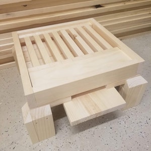 May include: A wooden beehive feeder with a removable tray and a slatted top. The feeder is made of unfinished wood and has a natural color.
