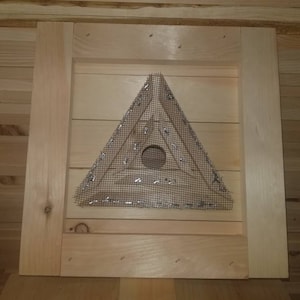 May include: A triangular wooden frame with a wire mesh screen inside. The frame is attached to a wooden wall.