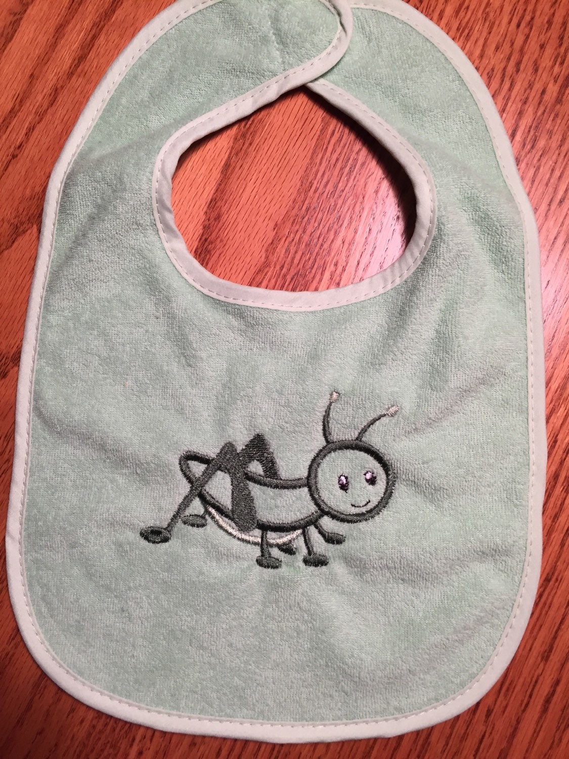 Embroidered greenbaby bib with grasshopper