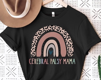 Może przedstawiać: Czarny T-shirt z wzorem tęczy z nadrukiem w panterkę. Tęcza ma serce w środku, a pod nią znajduje się napis "Cerebral Palsy Mama".