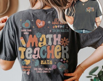 May include: A dark gray t-shirt with a colorful graphic that says "Math Teacher" and includes hearts, stars, butterflies, and rainbows. The text "It's a good day to do math" is also included on the shirt.