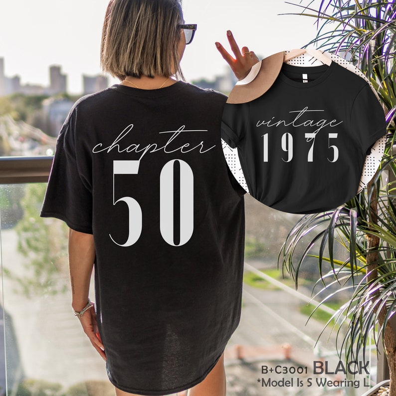 May include: Black t-shirt with white text that reads "chapter 50" on the back and "vintage 1975" on the front.