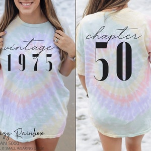 May include: A tie-dye t-shirt with the text "vintage 1975" on the front and "chapter 50" on the back. The shirt is a hazy rainbow color.