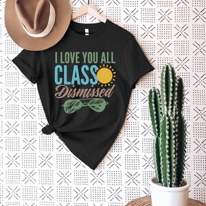 May include: Black t-shirt with the text "I love you all Class Dismissed" in white and blue lettering. A yellow sun and green sunglasses are also on the shirt.