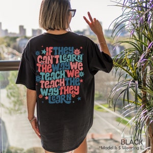 May include: Black t-shirt with a colorful graphic print that reads "If they can't learn the way we teach we teach the way they learn".