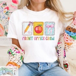 May include: White t-shirt with a colorful graphic that reads "FRONT OFFICE CREW." The graphic features a pencil, a red apple, and a pink bow. The shirt is made of Comfort Colors 1717 material.