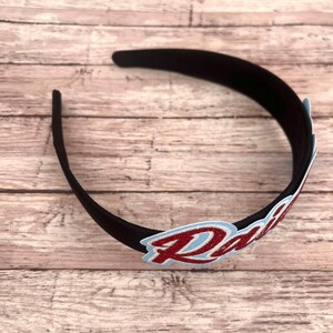 May include: A black headband with a red glitter "Radi" patch.