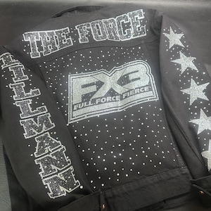 May include: Black denim jacket with silver glitter embellishments. The back features "THE FORCE" and "FX3 FULL FORCE FIERCE" designs. The sleeves have star and "ILLMAN" details. Rhinestones are scattered across the jacket.