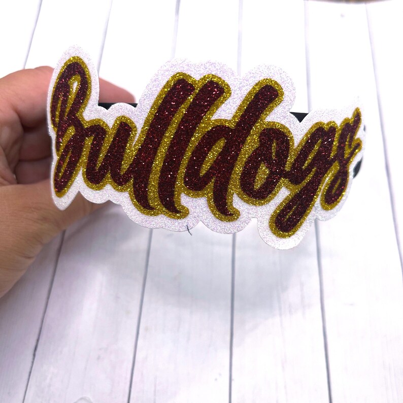 May include: White headband with the word "Bulldogs" in red and gold glitter lettering.