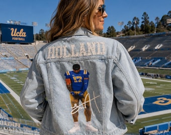 May include: A light blue denim jacket featuring the name HOLLAND in white beaded lettering across the upper back. Below the name is a graphic of a football player in a blue and gold uniform with the number 17 and a white signature overlay.