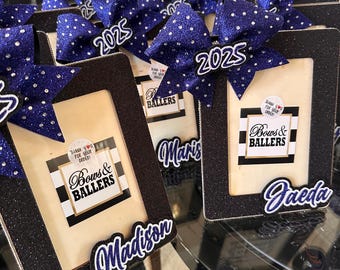 May include: Black glitter picture frames with blue and white polka dot bows, personalized with names and the year 2025. The frames have a white background with black and white stripes and the text "Thank you for your order! Bows & Ballers".