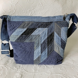 May include: A blue denim patchwork tote bag with a long strap. The bag is made of different shades of blue denim and has a quilted design.