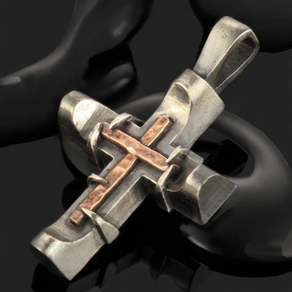 Hand-forged mixed sterling silver and copper cross with visible hammer marks — genuinely artisan craft with rugged, one-of-a-kind character.