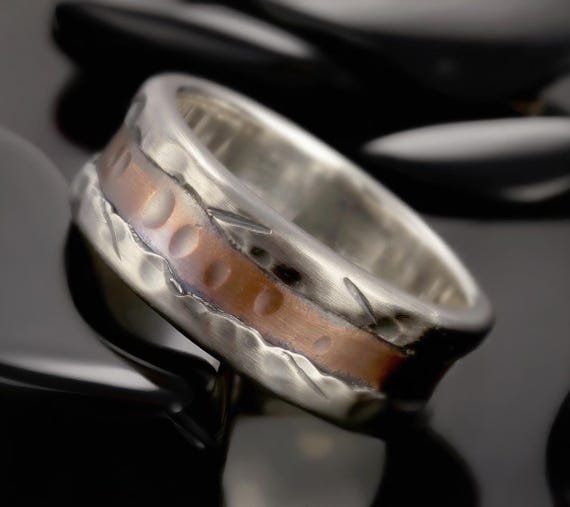 Hand-forged two-metal wedding band where the hammer marks and mixed silver/copper patina make every ring genuinely one-of-a-kind.