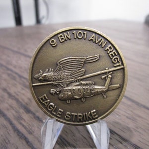 May include: A bronze coin with a helicopter and eagle design. The coin reads "9 BN 101 AVN REGT EAGLE STRIKE".