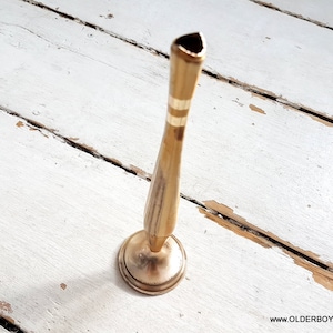 May include: A gold metal vase with a narrow neck and a wide base. The vase has a simple design with a few horizontal lines around the neck.