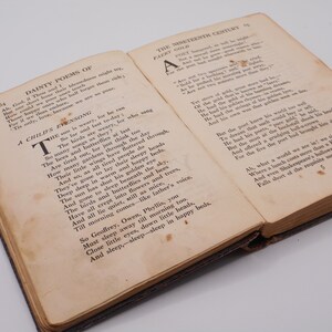 K&ouml;nnte beinhalten: Ein offenes Buch mit vergilbten Seiten, das ein Gedicht mit dem Titel "A Child's Evensong" und ein weiteres Gedicht mit dem Titel "Faery Gold" zeigt. Das Buch ist in braunes Leder gebunden und hat einen abgenutzten, antiken Look.