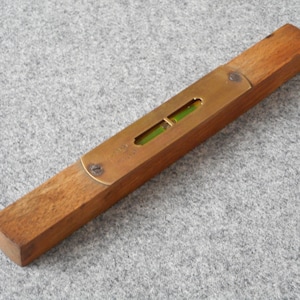 May include: A wooden level with a brass inlay and a green bubble level. The level is about 12 inches long.
