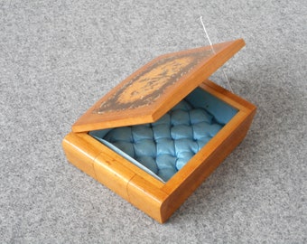 Caja de madera vintage con motivos de pájaros y fuente, interior de tela azul.