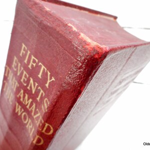 May include: A red hardcover book with gold lettering on the spine that reads "Fifty Events That Amazed The World".