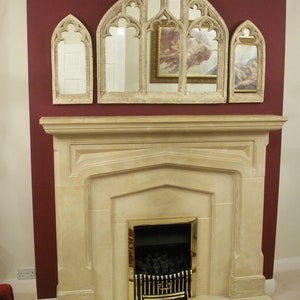 May include: A white stone fireplace with a gold-trimmed black fireplace insert. The fireplace is decorated with three arched mirrors with ornate frames.