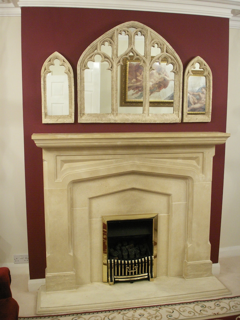 May include: A white stone fireplace with a gold-trimmed black fireplace insert. The fireplace is decorated with three arched mirrors with ornate frames.
