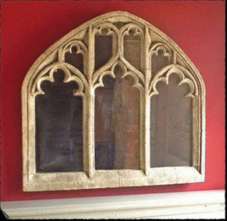 May include: A white wooden arched window frame with a Gothic design. The frame has three arched openings with intricate carvings and a decorative top.