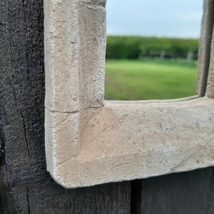 May include: Close-up of a white painted wooden frame with a textured surface. The frame is attached to a dark wood surface.