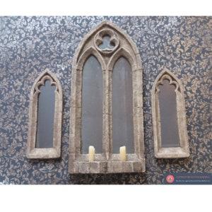 May include: Three arched stone framed mirrors with a gothic design. The centre mirror is larger than the two side mirrors. The mirrors are set against a dark patterned background.