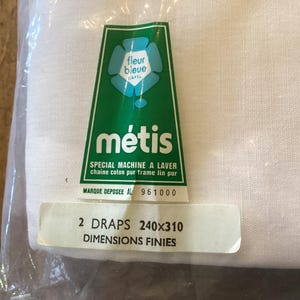 Puede incluir: Tela blanca en una bolsa de plástico con una etiqueta verde. La etiqueta dice "métis" y "SPECIAL MACHINE A LAVER chaine coton pur frame lin pur". Una etiqueta más pequeña indica "2 DRAPS 240x310 DIMENSIONS FINIES".