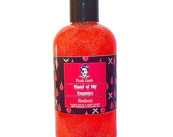May include: A red bottle of bath and body wash with a black label. The label features a cartoon illustration of a woman with a black eye and the text "Posh Goth Blood of My Enemies Bathory Blood Bath & Body Wash Net Weight 8 oz (226 g)".