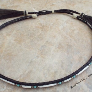 May include: A black and white braided horsehair necklace with turquoise and silver beads. The necklace has tassels on each end. "Knot-a-Tail.com" is printed on the bottom right corner of the image.