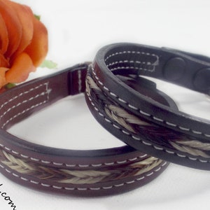 May include: Two leather bracelets with braided horsehair detailing. The bracelets are dark brown and black with white stitching. The background includes an orange rose and the website "Knot-a-Tail.com".