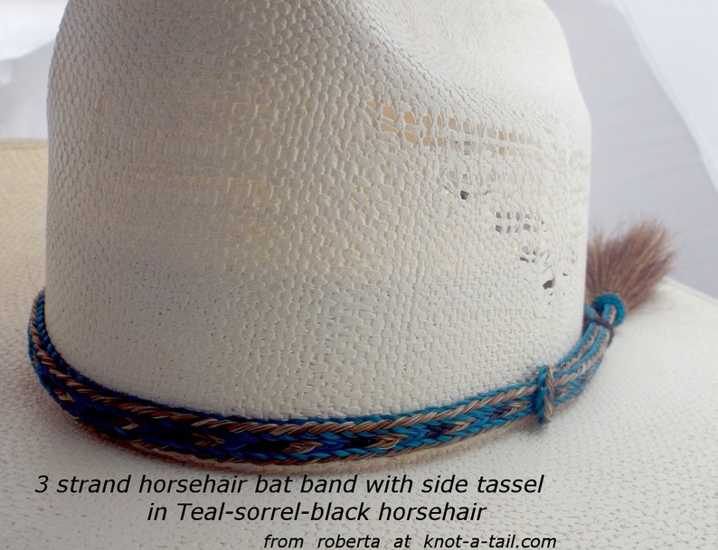 May include: A white cowboy hat with a teal, brown, and black horsehair hat band and a side tassel. The hat band is a 3 strand braid. The text on the image reads: "3 strand horsehair bat band with side tassel in Teal-sorrel-black horsehair from roberta at knot-a-tail.com"