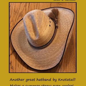 May include: A brown straw cowboy hat with a brown horsehair hatband. The hat has a black band around the brim and a brown leather band around the crown. The hat is sitting on a wooden surface.