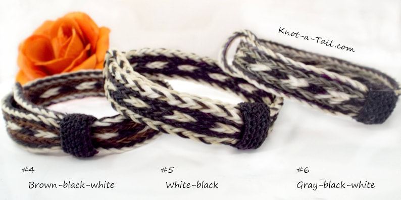 Puede incluir: Tres pulseras trenzadas de crin de caballo en marr&oacute;n, blanco y gris con detalles negros. Las pulseras est&aacute;n anudadas en los extremos.