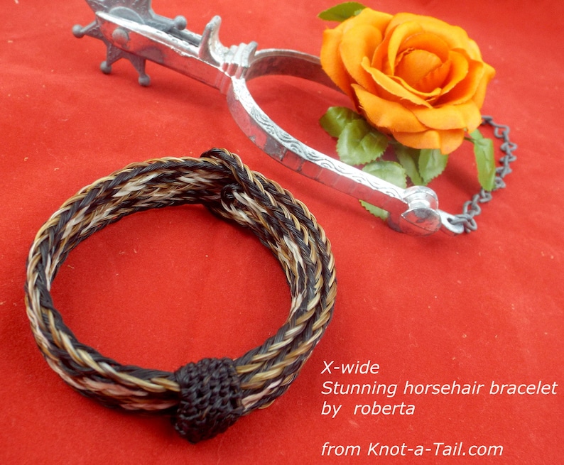 Puede incluir: Un brazalete trenzado de crin de caballo en negro, marr&oacute;n y blanco con un cierre de nudo negro. El brazalete est&aacute; etiquetado como "X-ancho Impresionante brazalete de crin de caballo por roberta de Knot-a-Tail.com".