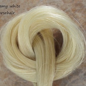 May include: Creamy white horsehair, a bundle of long, fine strands of hair in a light, creamy white color.