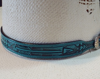 May include: Close-up of a white cowboy hat with a turquoise and black leather hatband. The hatband features an arrow and geometric design with a silver-colored buckle.