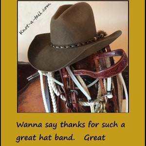 Puede incluir: Un sombrero de vaquero marr&oacute;n con una banda de pelo de caballo descansa sobre una silla de montar y un aparejo. La banda del sombrero presenta un patr&oacute;n decorativo. La imagen incluye el texto "Stunning Horsehair hat band" y "knot-a-tail.com".