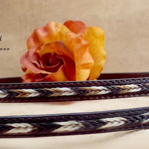 May include: Two brown leather cowboy hat bands with a braided horsehair insert. The bands are stacked on top of each other and have a white and brown braided design. The text "Remarkable Horsehair insert Leather Cowboy hat band Think ***STUNNING*** ***" is visible in the image.
