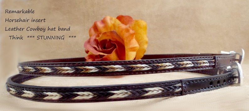 May include: Two brown leather cowboy hat bands with a braided horsehair insert. The bands are stacked on top of each other and have a white and brown braided design. The text "Remarkable Horsehair insert Leather Cowboy hat band Think ***STUNNING*** ***" is visible in the image.