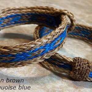 Puede incluir: Dos pulseras trenzadas en un esquema de color marr&oacute;n canela y azul turquesa. Las pulseras est&aacute;n hechas de crin de caballo y est&aacute;n atadas juntas con un nudo. #14