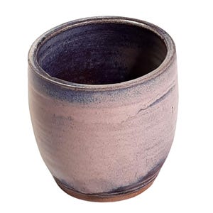 May include: A handcrafted ceramic tumbler with a rounded form. The exterior is a pale pink with delicate swirling patterns, and the interior and rim are a deep indigo. The base has a natural, unglazed brown finish.