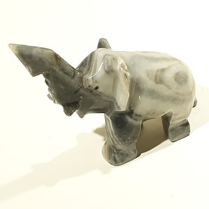 May include: A small, white and gray marble elephant figurine. The elephant has a long trunk and is standing on all four legs.
